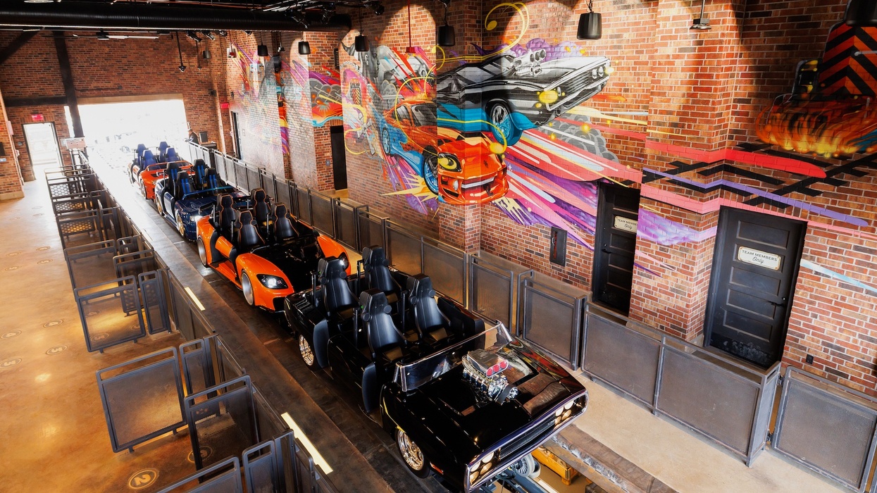 Theme park ride station for Fast & Furious: Hollywood Drift with vibrant car mural on brick walls.