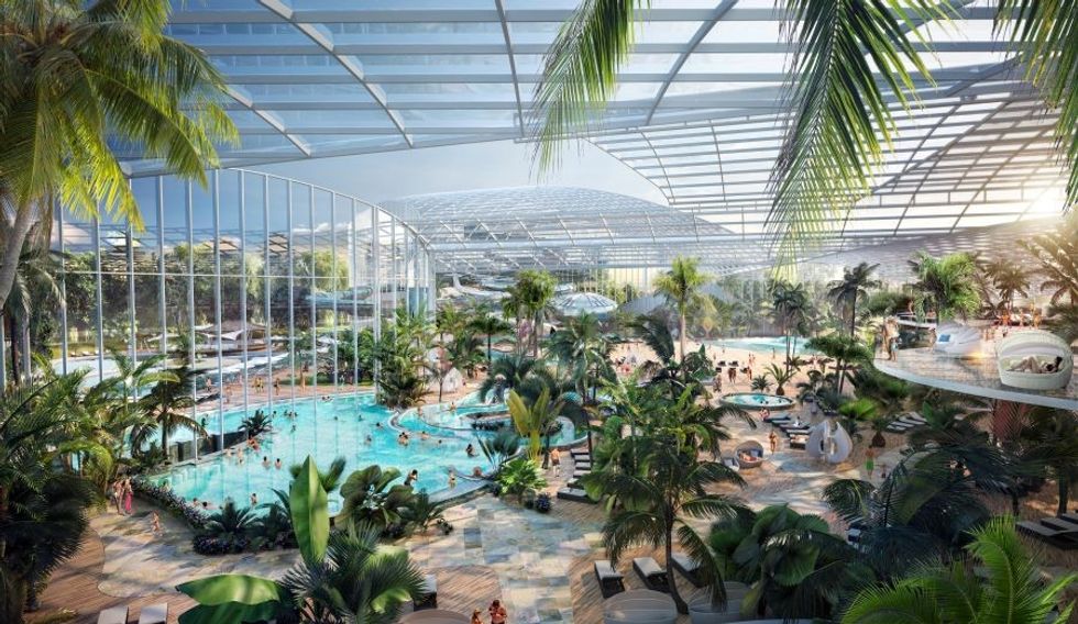 Therme Manchester indoor water park with large pools, palm trees, and people enjoying leisure activities.