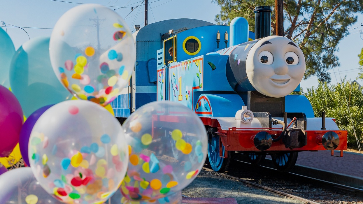 Thomas the Tank Engine character next to colorful balloons outdoors.