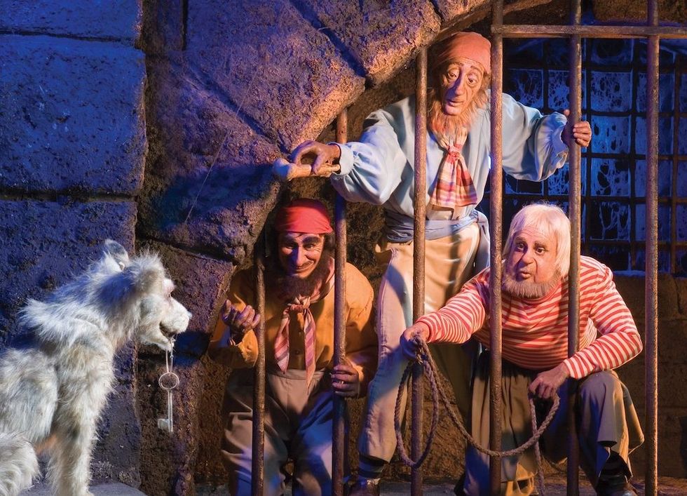 Three animatronic pirate prisoners in a cell reach for keys held by an animatronic dog outside the bars. Pirates of the Caribbean Disneyland California