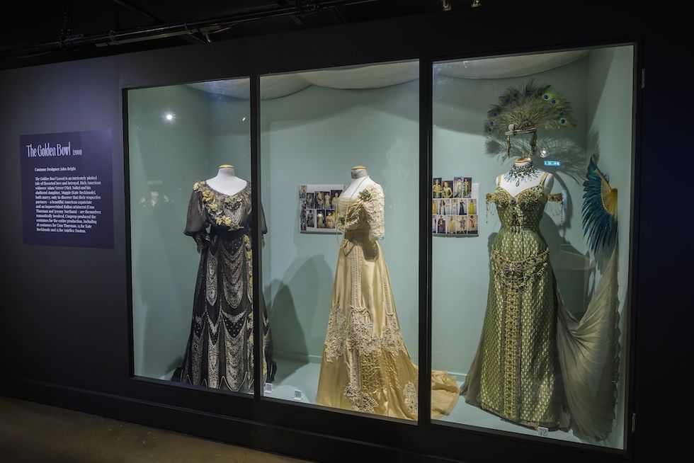 Three elegant period costumes displayed in a glass exhibit case, Costume Couture touring exhibition