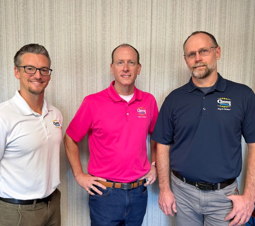 Three men smiling and standing together, wearing branded polo shirts in white, pink, and navy.