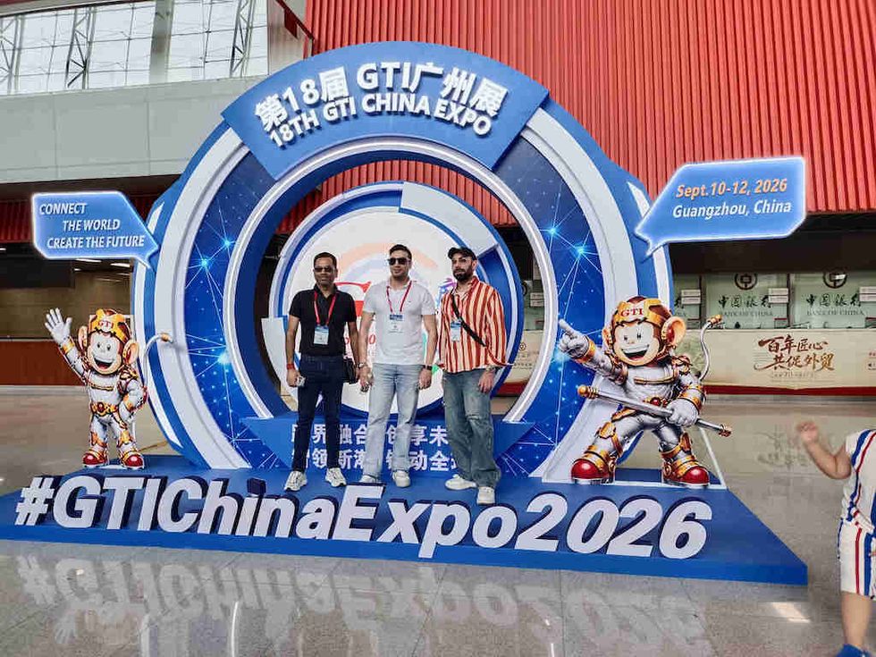 Three people at GTI China Expo 2026 display in Guangzhou, flanked by cartoon astronaut figures.