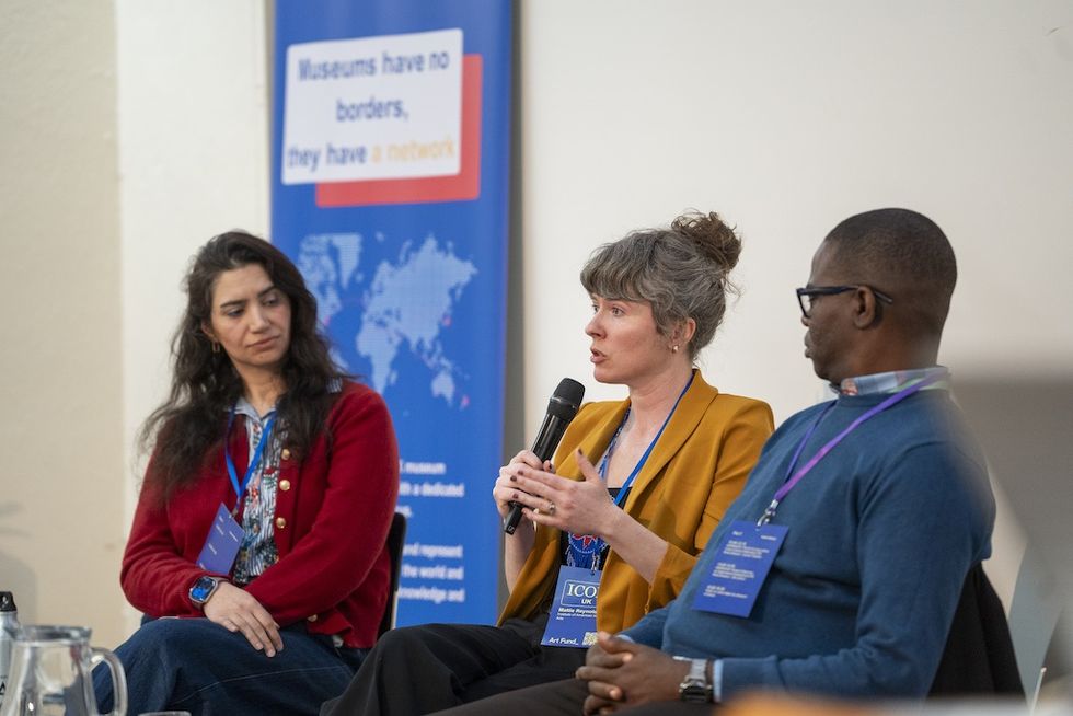 Three people engaged in a panel discussion at a museum-related event.
