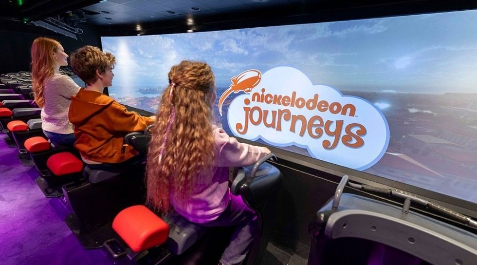 Three people enjoying a Nickelodeon Journeys interactive ride attraction.