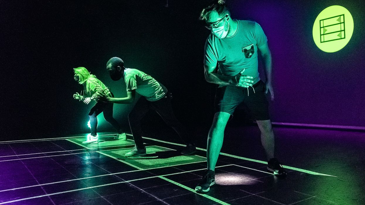 Three people illuminated by neon lights in a dark room, preparing to sprint.