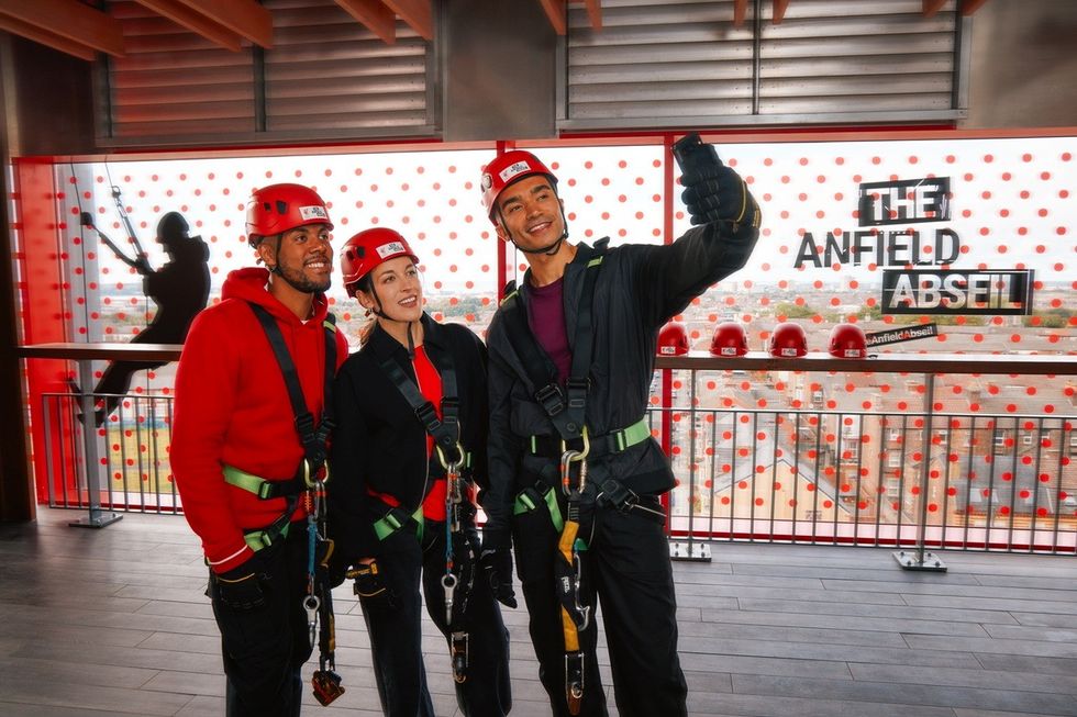 Three people in harnesses and helmets taking a selfie at Anfield Abseil.