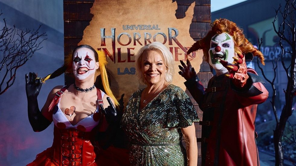 Three people pose at Universal Horror Nights, two in clown costumes, one in a sparkly dress.
