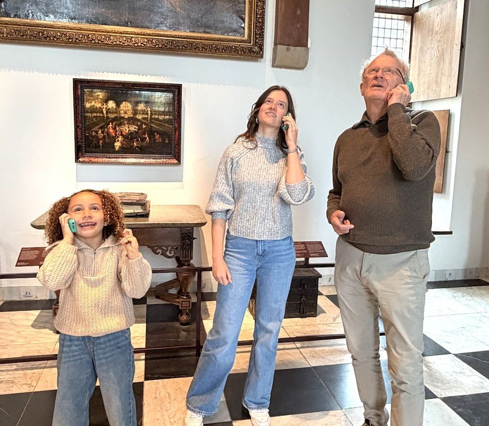Three people using audio guides in an art gallery.
