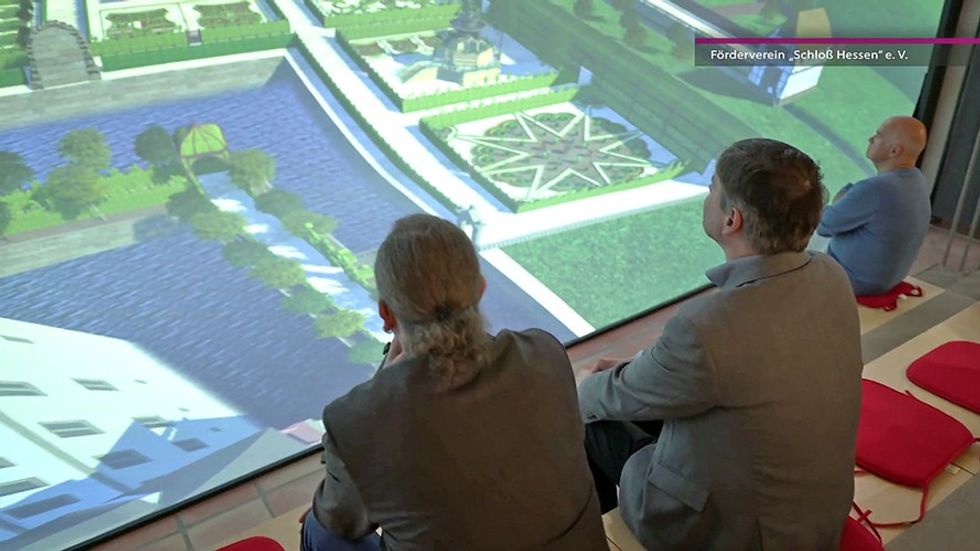 Three people view a large screen displaying a detailed virtual landscape model.