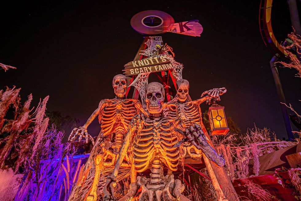 Three skeletons at Knott's Scary Farm entrance, one holding a lantern.