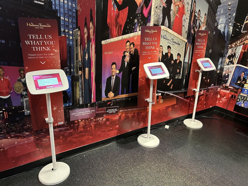 Three touchscreen kiosks at Madame Tussauds for visitor feedback surveys.
