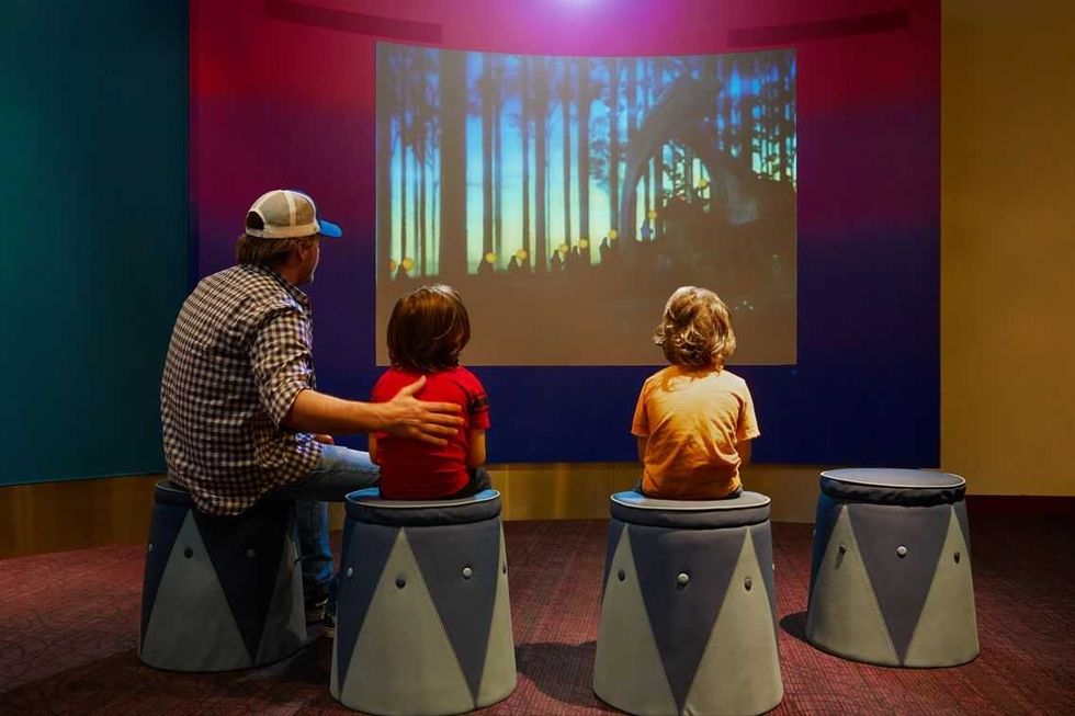 Three visitors watching an animated video