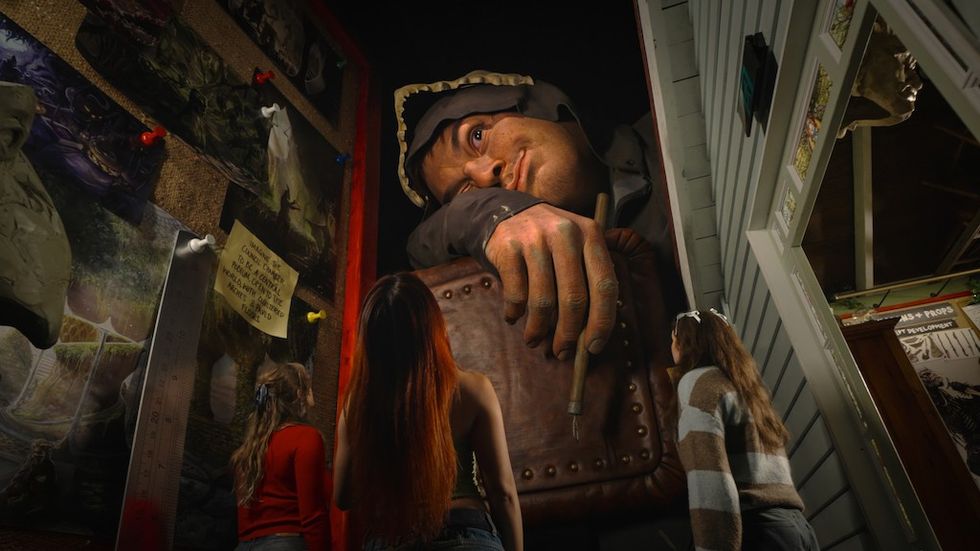 Three women look at a giant, realistic sculpture of a man holding a pen at W\u0113t\u0101 Workshop Unleashed