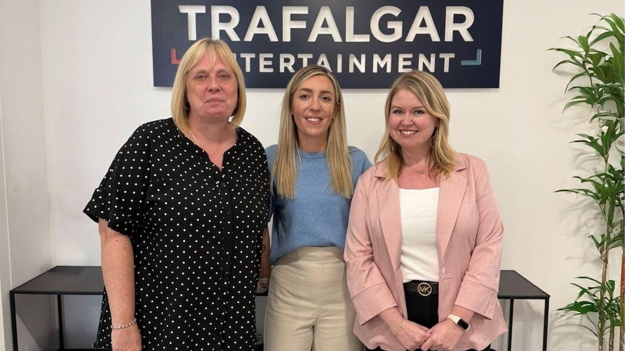 Three women standing at Trafalgar Entertainment office, smiling at the camera.