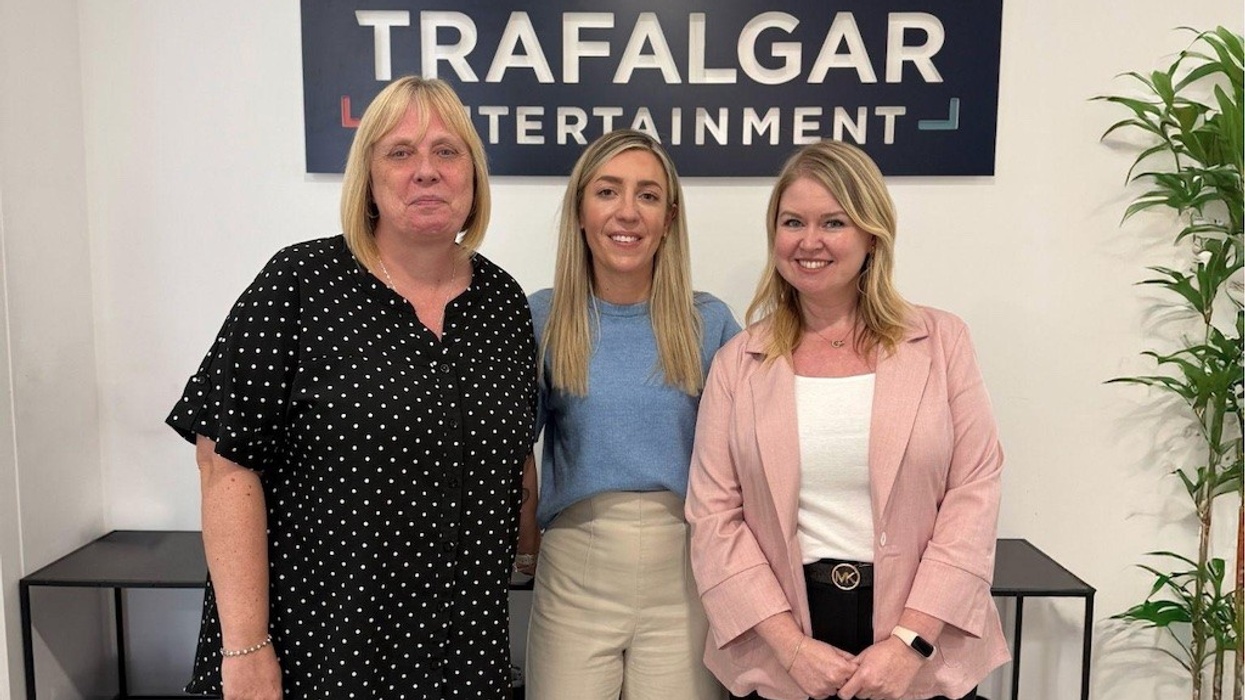 Three women standing at Trafalgar Entertainment office, smiling at the camera.