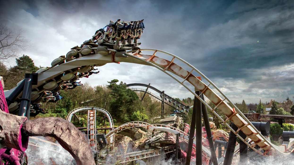Thrilling roller coaster ride called Nemesis with looping tracks under a dramatic, cloudy sky.