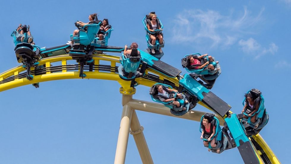 Thrilling roller coaster ride with people enjoying a loop under a clear blue sky.
