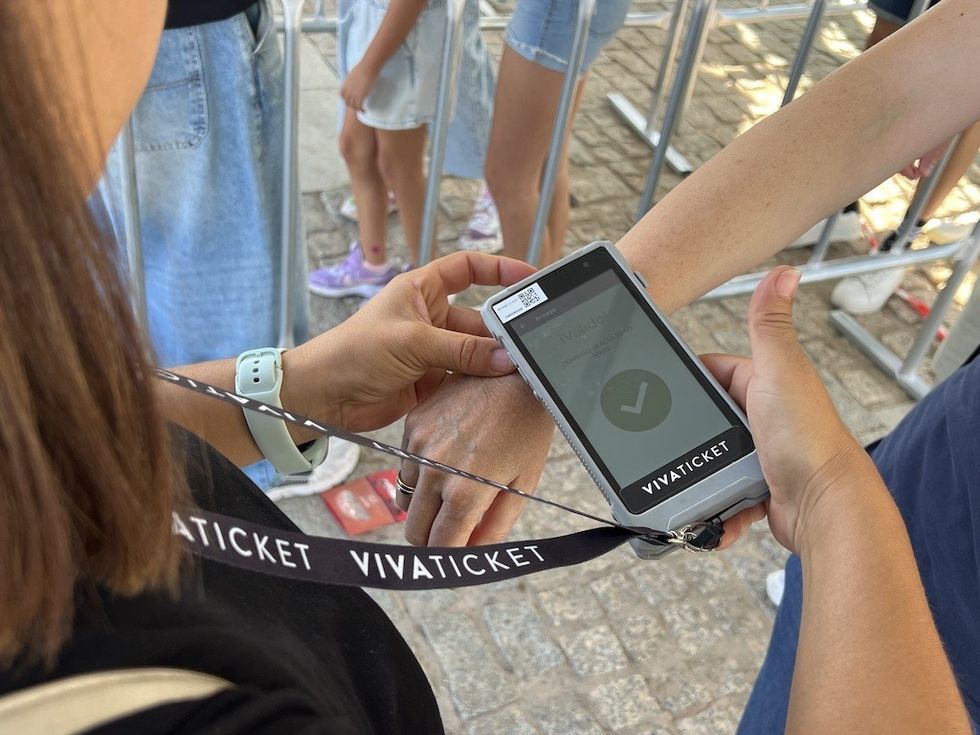 Ticket scanner verifying wristband at an event entrance.