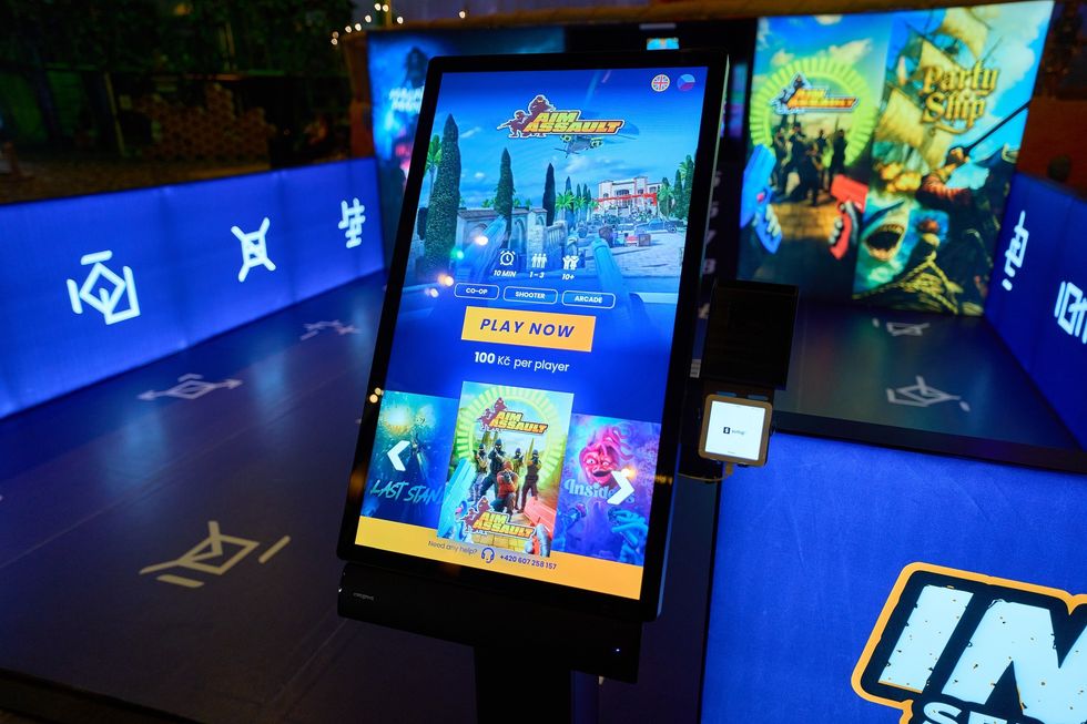 Touchscreen arcade game interface with "Play Now" button and vibrant game graphics.