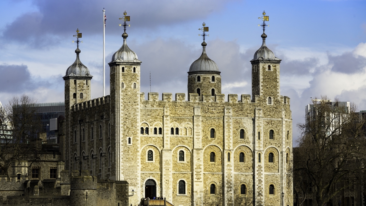 Tower of London with four turreted structures under a cloudy blue sky