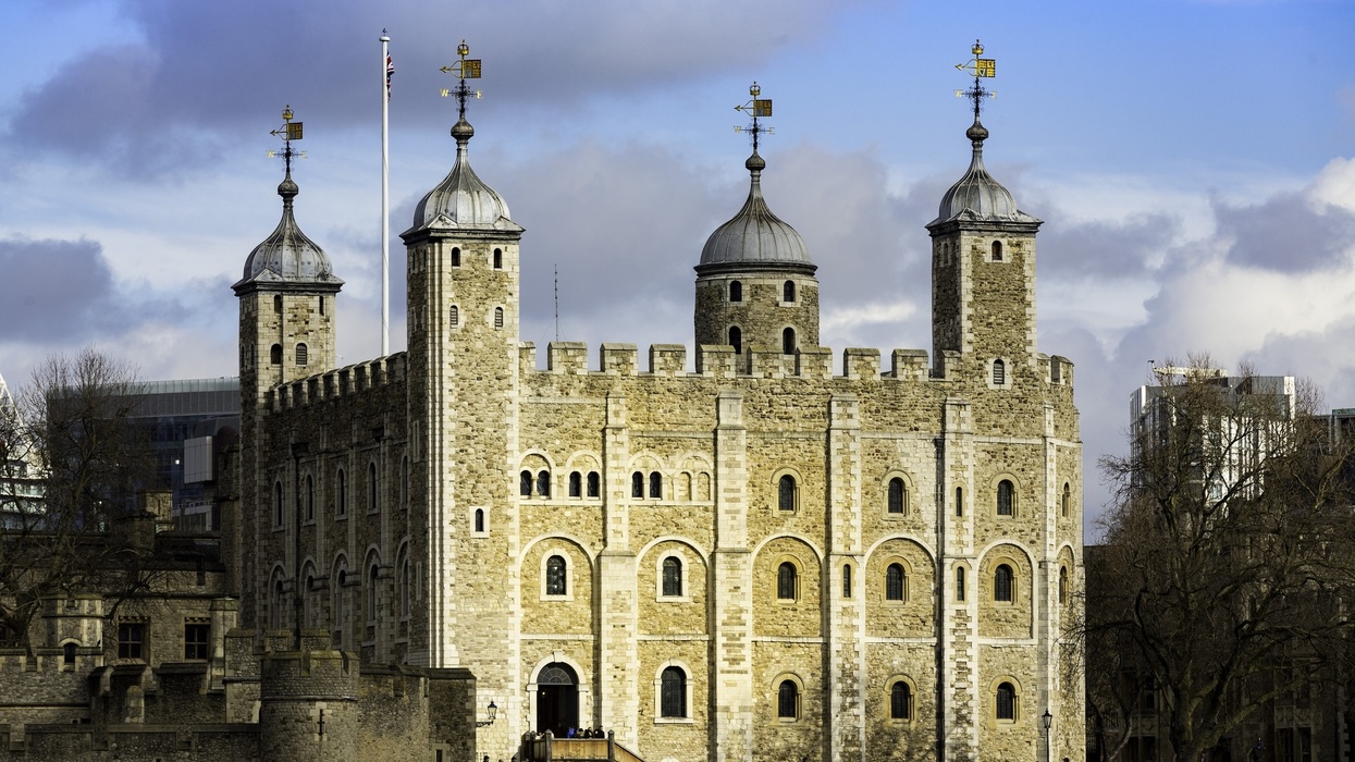 Tower of London with four turreted structures under a cloudy blue sky
