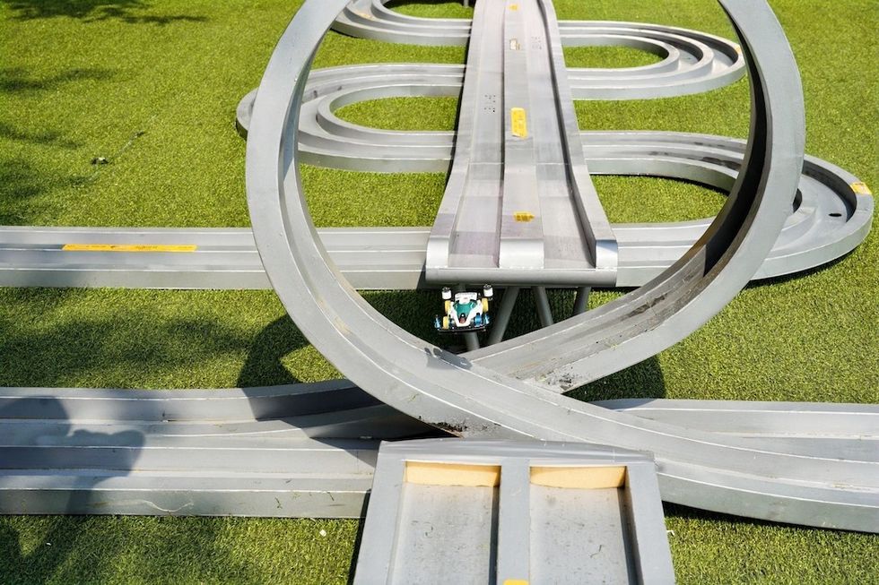 Toy car on gray looping track on grass.