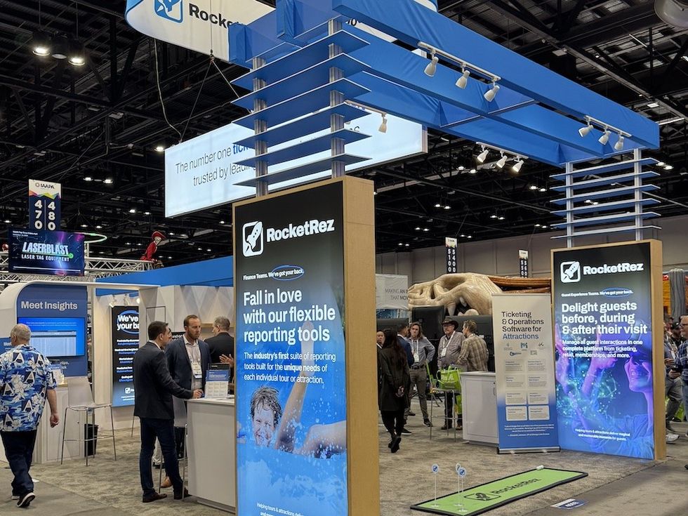 Trade show booth with RocketRez signage and attendees interacting.