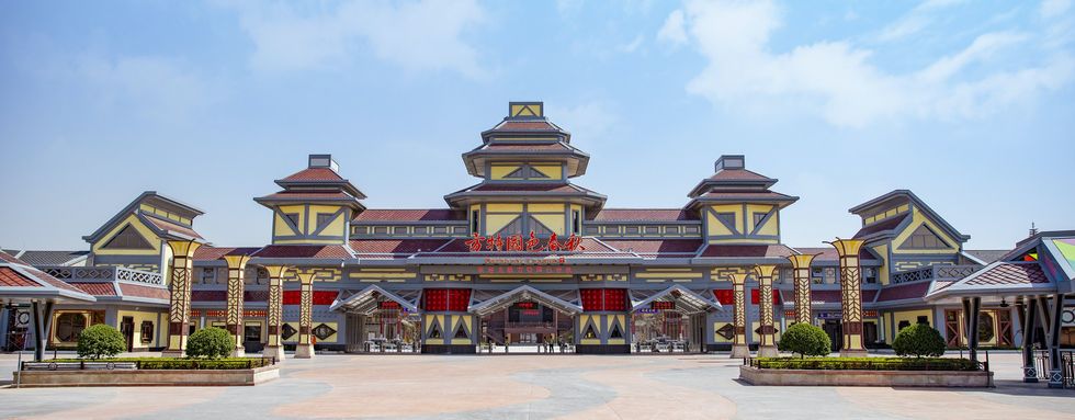 Traditional-style theme park entrance with intricate architecture under a blue sky.