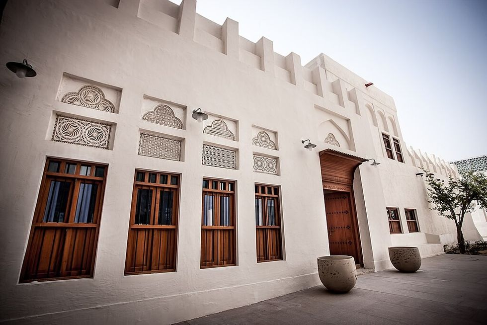 Traditional white building with wooden doors and intricate window designs at Msheireb Museums