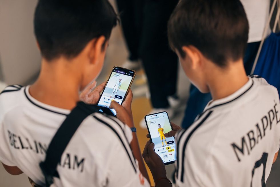 Two boys in jerseys using mobile gaming apps on their phones.