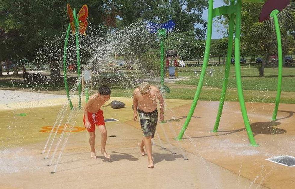 two boys run under water jets at lac de l'uby - waterplay solutions aquatic play splashpad