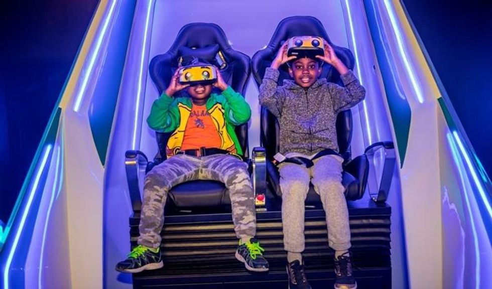 two boys wearing headsets sit in immotion vr pod at legoland discovery center boston usa