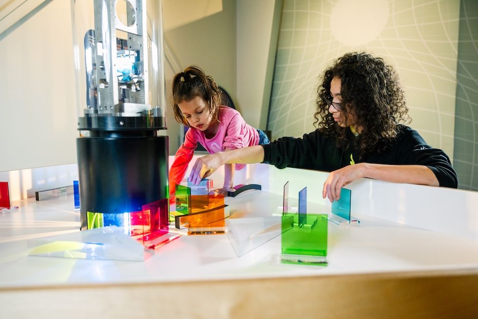 Two children engage with colorful glass panels in a science exhibit at LIGO Exploration Center