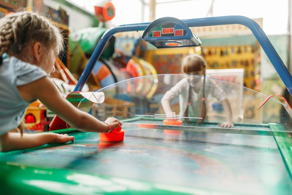 Two children playing air hockey in an arcade.