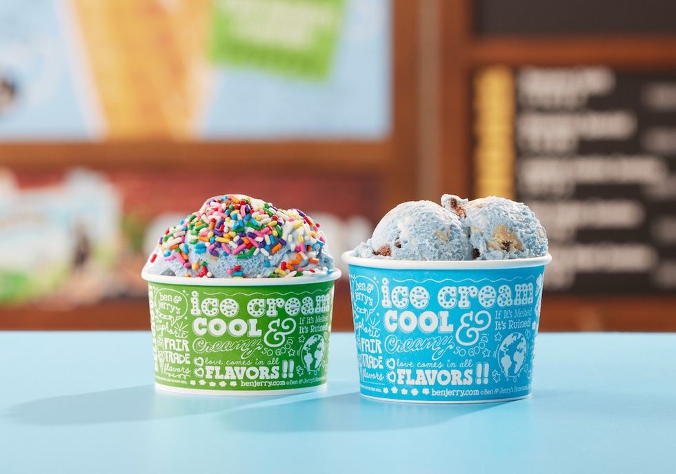Two cups of colorful ice cream on a blue table.