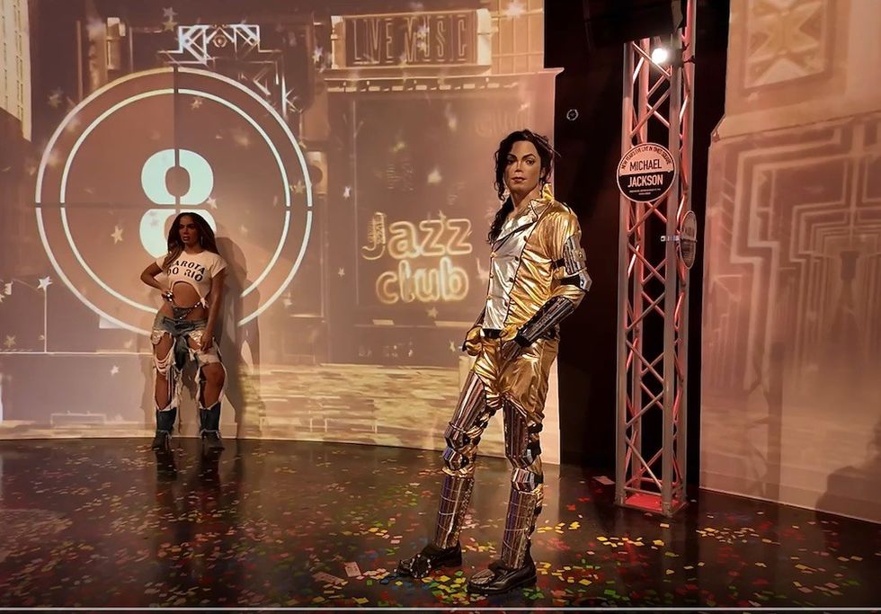 Two figures pose in front of a "Jazz Club" backdrop with a countdown clock.