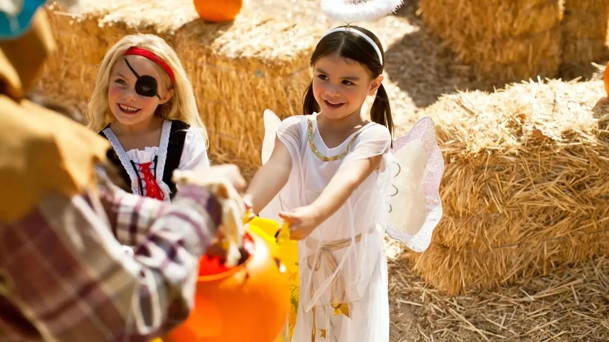 Two girls, dressed as an angel and pirate, trick-or-treat near hay bales at Six Flags Darien Lake