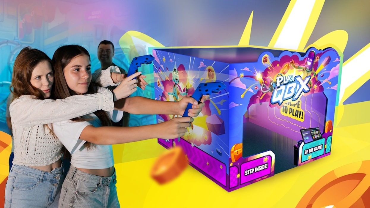 Two girls playing an arcade shooting game in the QBIX Play system with colorful graphics.