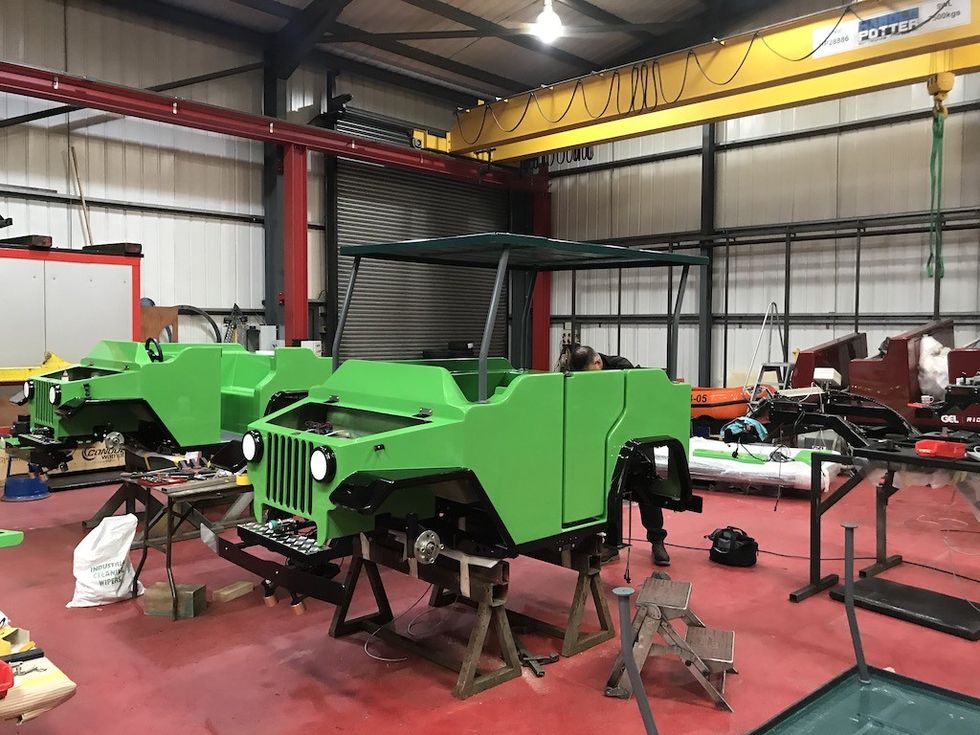 Two green off-road vehicles being assembled in a workshop.