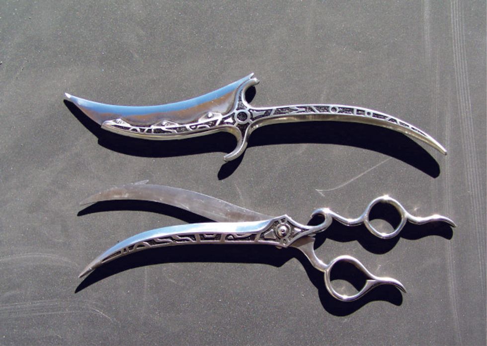 Two intricate, silver ornamental daggers on a dark surface.