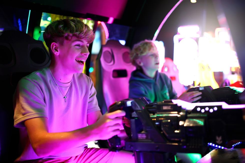 Two kids enjoying an arcade racing game with bright neon lights.