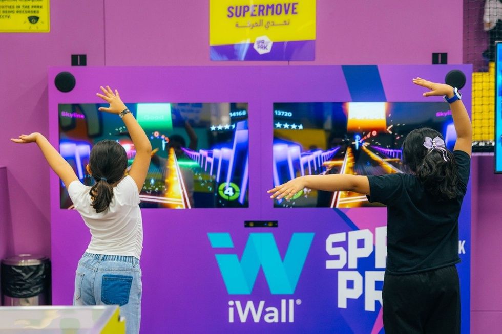 Two kids playing an interactive dance game on large screens.
