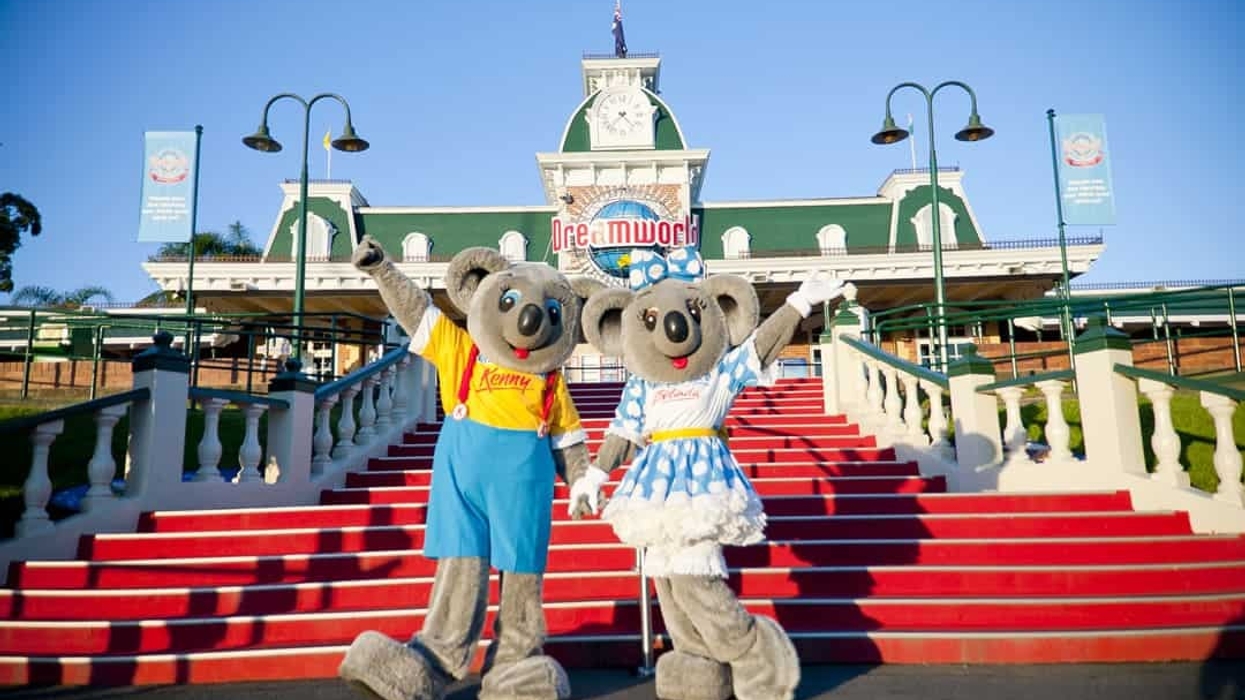 Two koala mascots on red steps in front of Dreamworld entrance.