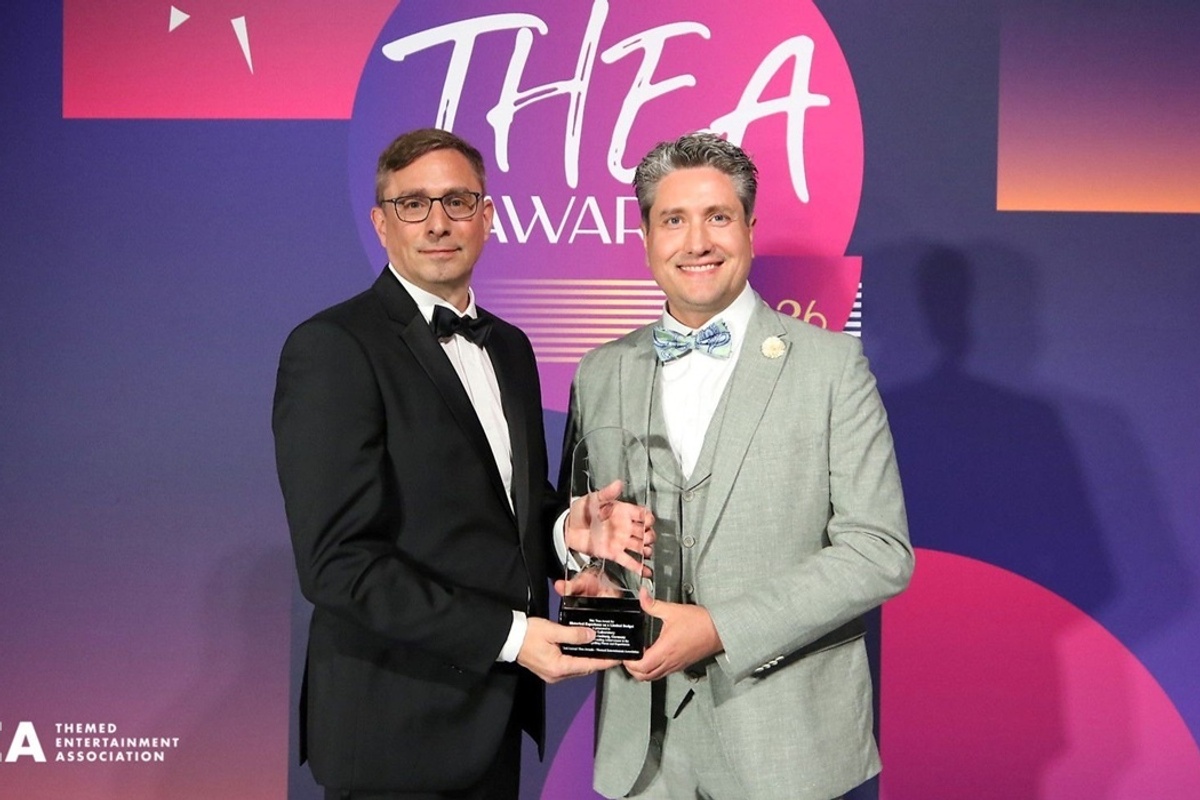 Two men holding an award at the TEA Thea Awards ceremony.