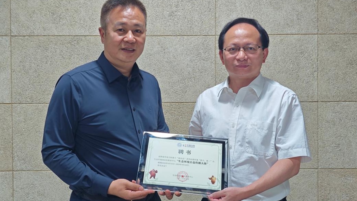 Two men, named Chen Zuyao and Zhang Huaping, holding a framed certificate in front of a tiled wall.