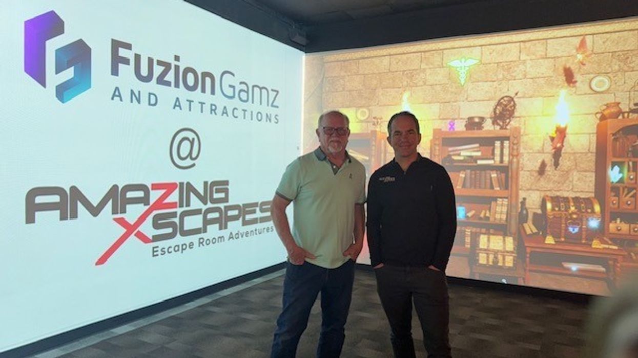 Two men stand in front of a Fuzion Gamz and Amazing Xscapes display.
