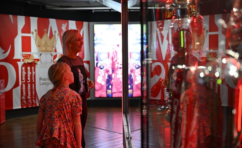 Two people admire trophies in a Premier League museum exhibit.