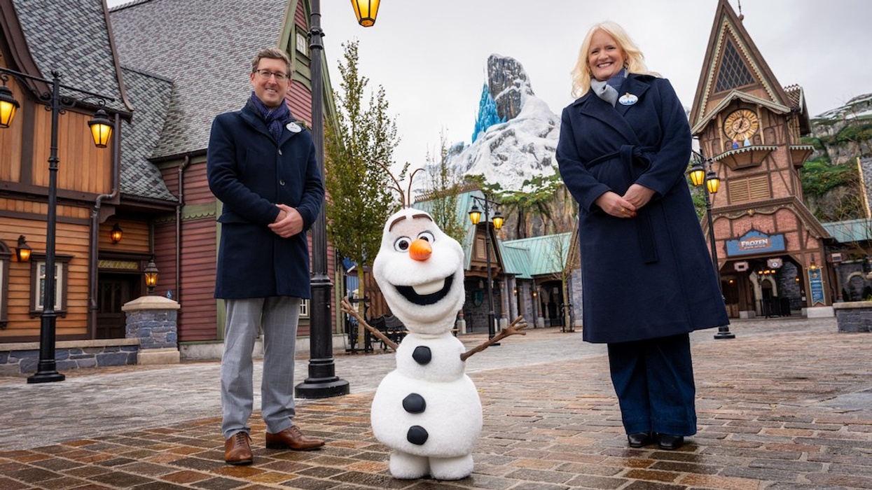 Two people and Olaf at a Frozen-themed area in Disneyland with snowy mountain backdrop.