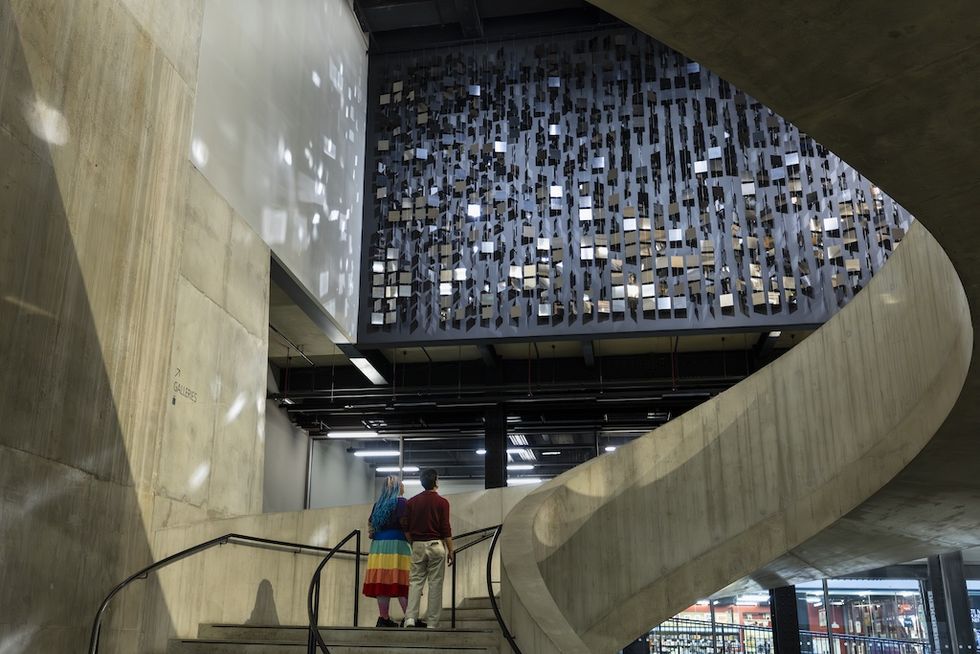 Two people ascending a concrete spiral staircase beneath Julio Le Parc artwork at Tate Modern